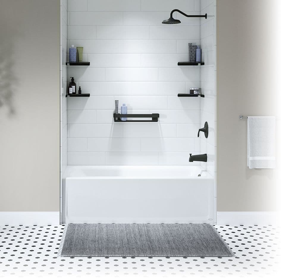 A white bathtub and shower with black fixtures and caddies.